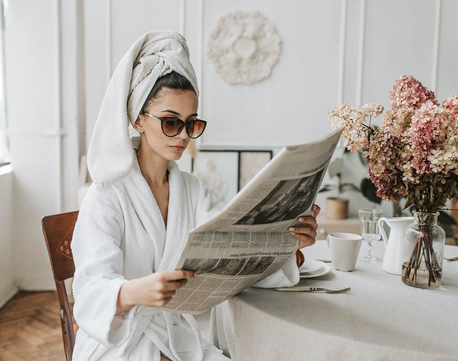 Meine Wanddeko Newsletter 10€ Gutschein wird von einer hübschen Frau im Bademantel die eine Zeitung liest dargestellt