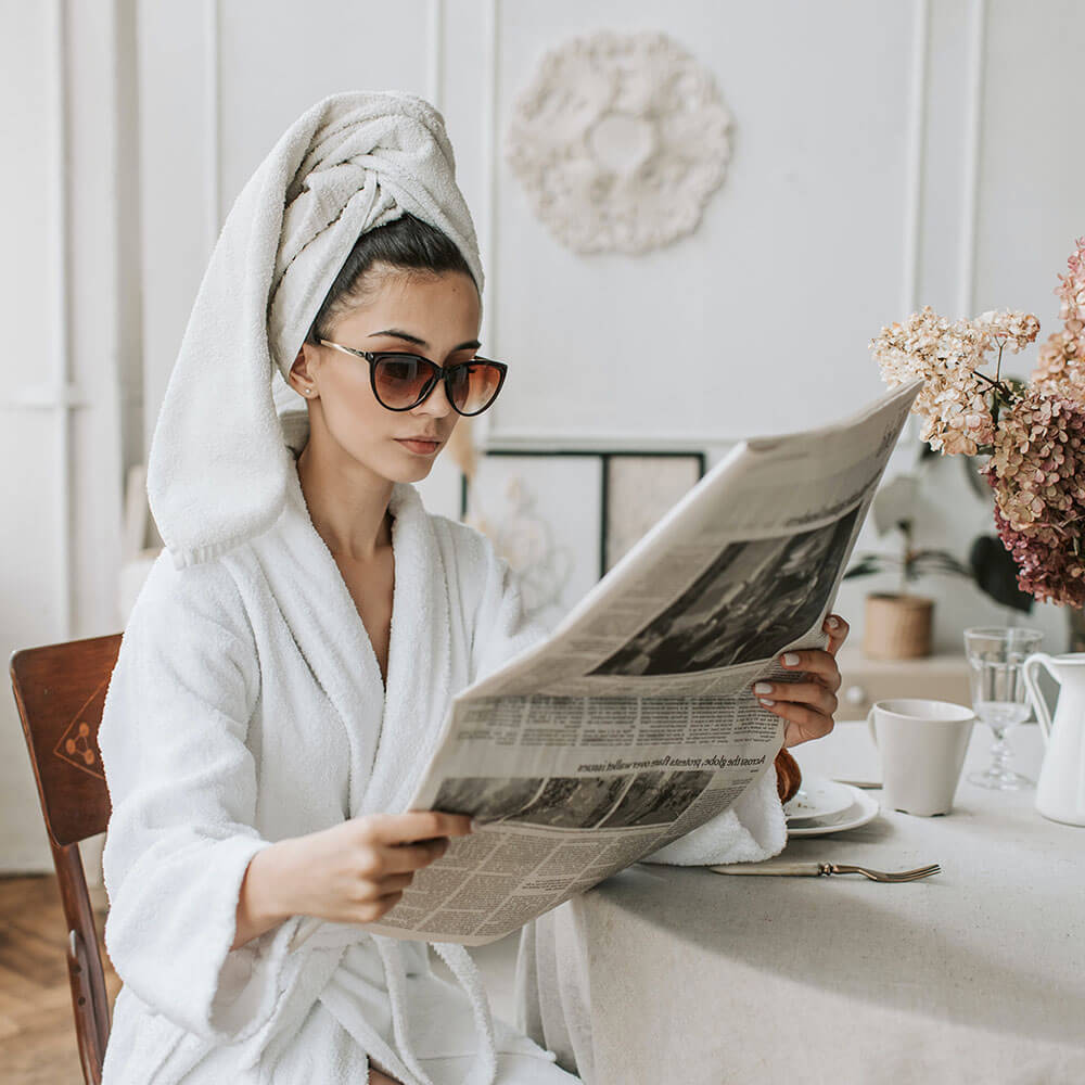 Meine Wanddeko Newsletter wird von einer hübschen Frau dargestellt die eine Zeitung liest im Bademantel