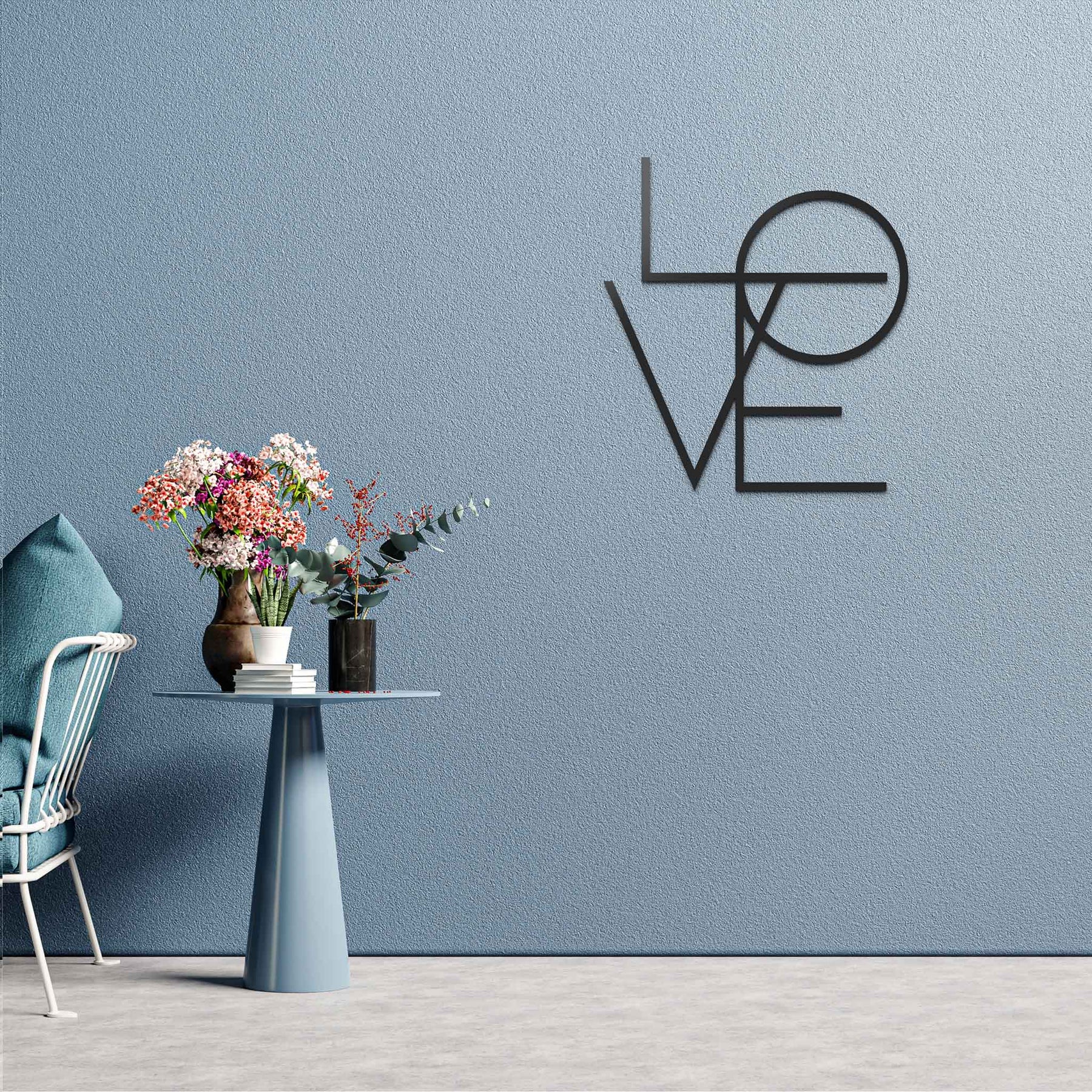 Mesi Love an einer blauen Wand mit starker Struktur neben einem sehr schlichten Sofa mit einem Beistelltisch mit Blumen